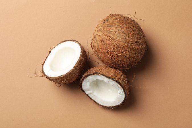 Coconuts on brown background, top view. Tropical fruit