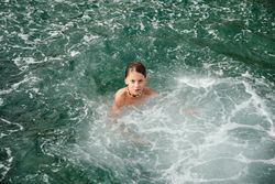Shirtless boy in the sea looking at the camera and relaxing