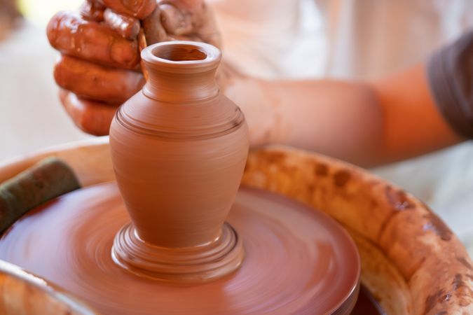 Person making clay pot on round table during daytime