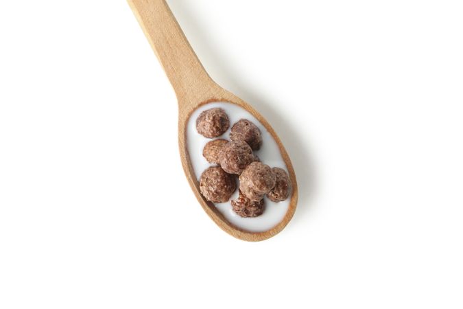 Spoon with corn balls and milk isolated on plain background
