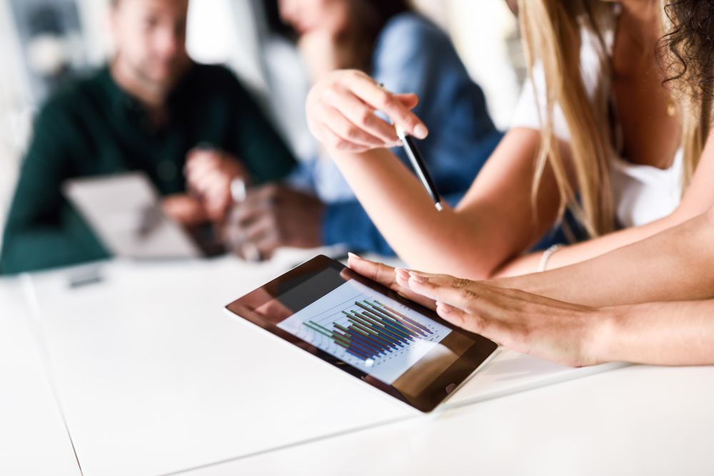 Close up of a student’s hands with group working on tablet