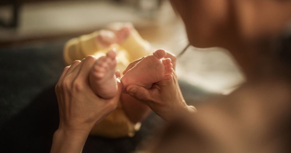 Close up on the Hands of an Affectionate Mother Massaging the Little Feet of her Baby with Tenderness and Love.