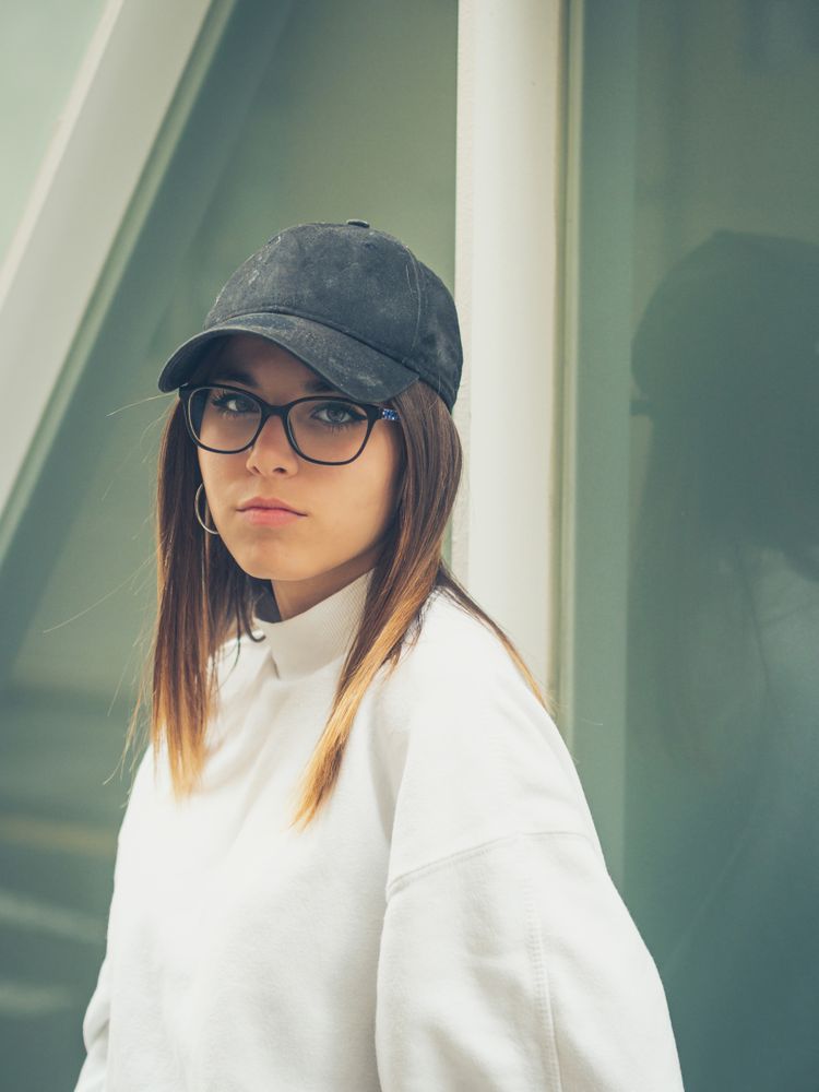 Young woman with glasses standing against wall
