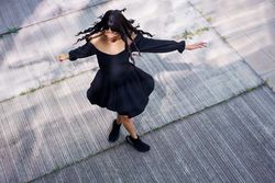 Elegant woman dancing in circles raising hands in the street