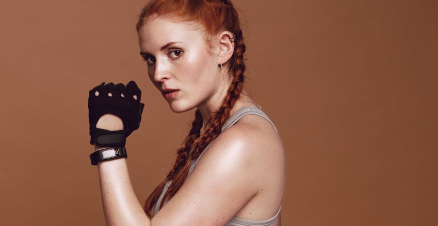 Tough young woman with red braided hair wearing workout gloves