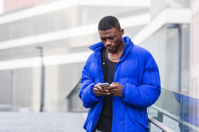 Stylish Black man chatting on social media on cellphone