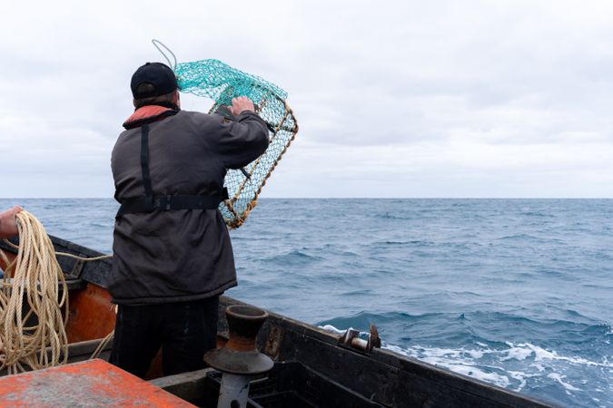 Fisherman using container with net to fish lobsters