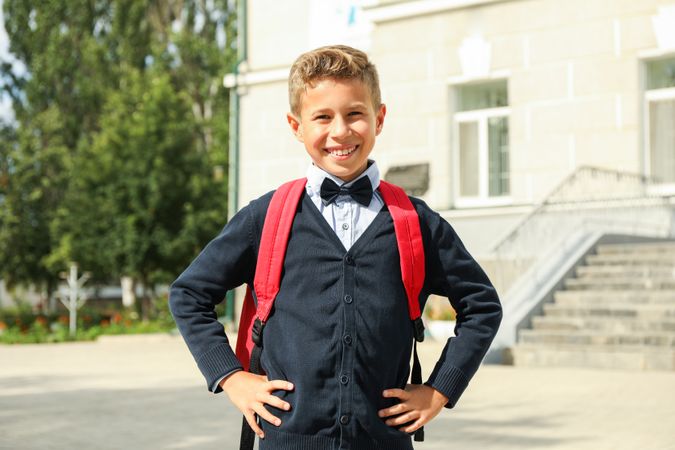 Boy with backpack against school building, space for text