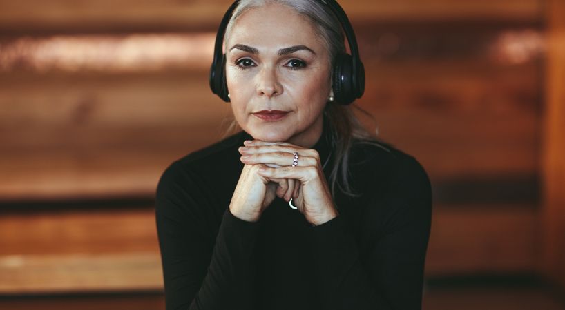 Closeup portrait of mature woman listening music on headphones