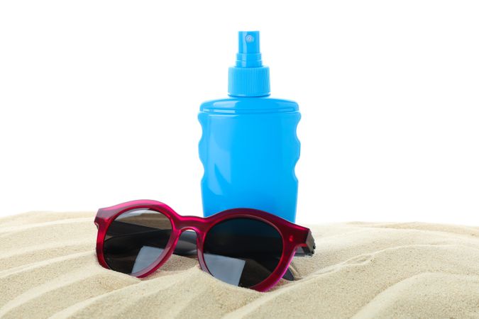 Sunscreen with sunglasses on clear sea sand isolated on plain background. Summer vacation