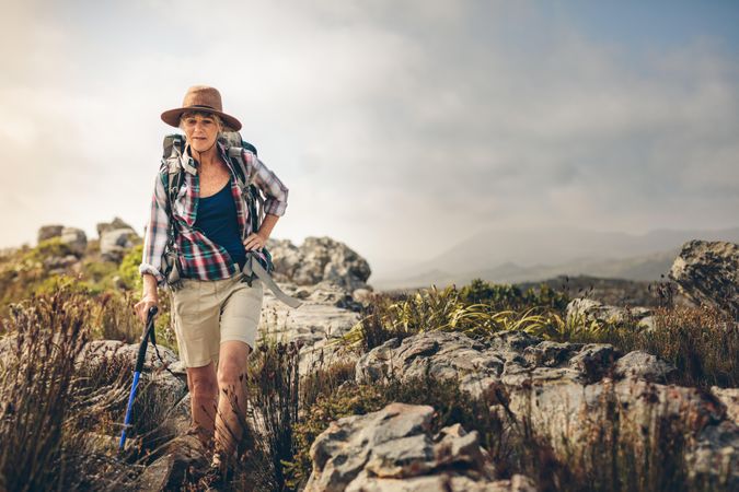 Mature woman wearing hiking gear walking on a rocky hill