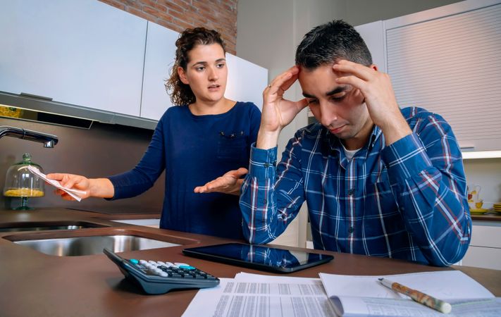 Couple in conflict working through their bills together in the kitchen