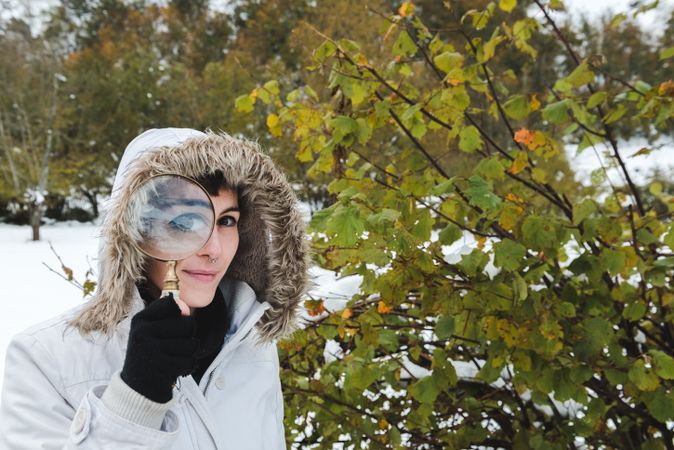 Smiling woman looking through magnifier in winter