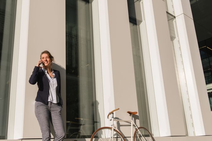Cheerful female manager speaking on smartphone on street