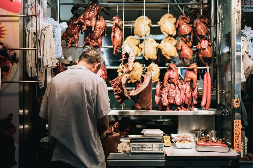 Back view of man standing against poultry butchery stand