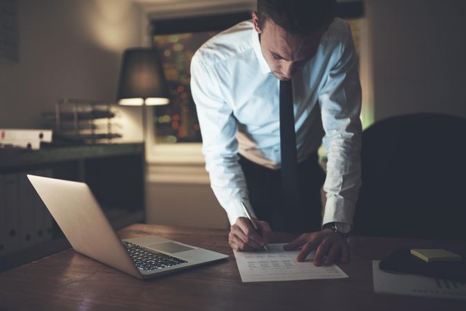 Man working on documents while standing over his desk