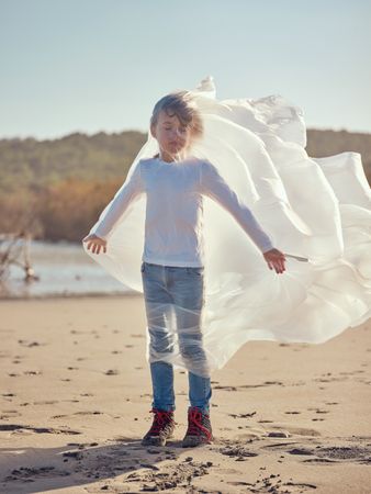 Boy with plastic bag around body on beach