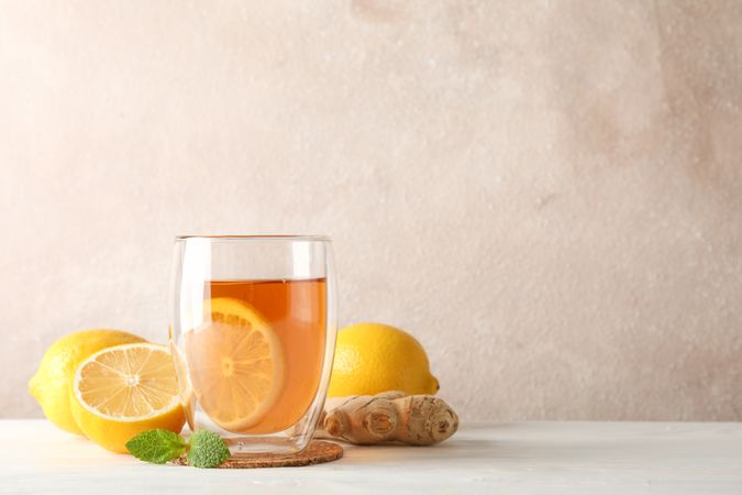 Glass of tea with lemon, mint, honey, dipper and ginger on wooden background ,copy space