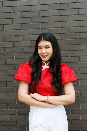 Portrait of Asian female in red shirt standing in front of brick wall