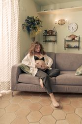 Pregnant woman relaxing at home on the sofa touching her belly.