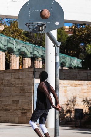 Anonymous Black man playing basketball on sports ground