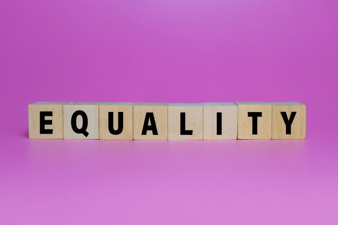 equality words on wooden blocks isolated on pink background