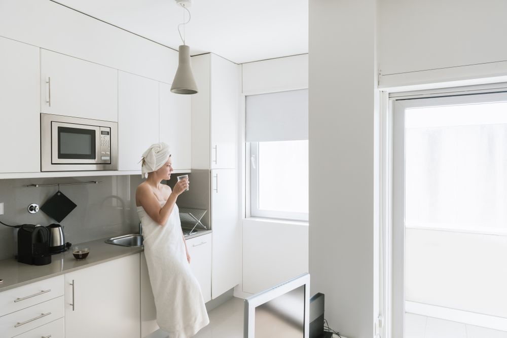 Pensive serene woman having refreshment with water in comfortable kitchen