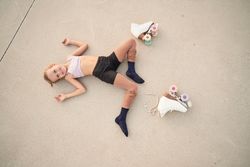 Girl lying on concrete ground near quad roller skates