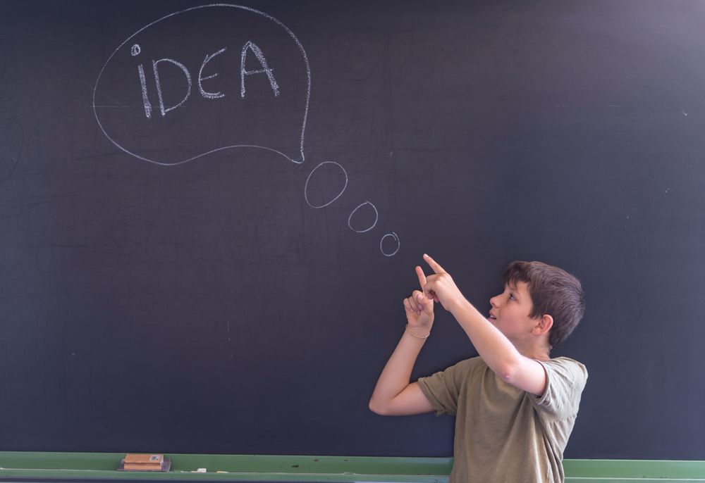 Boy standing at board with "idea" written in chalk