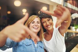 Two female friends posing through a square made with their hands