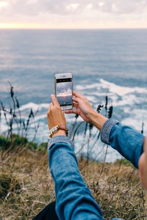 Female tourist taking shot of sea in twilight
