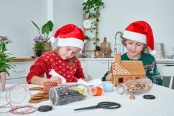 Cute children making gingerbread house in kitchen