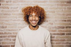Portrait of a young man with a brick wall background.