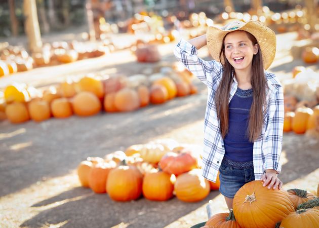 Girl Wearing Cowboy Hat Enjoying The Pumpkin Patch on a Sunny Fall Day.