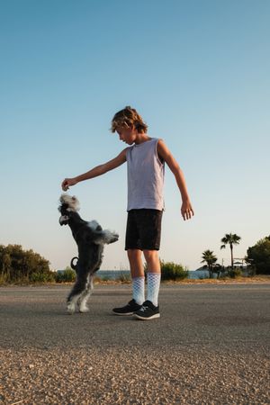 Boy spending time with dog on road in countryside