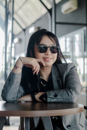 Stylish young woman in trendy sunglasses reflects peaceful momen