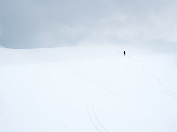 Unrecognizable lonely traveler walking on snowy hill