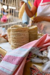 Crop cook and stacks of flatbreads at market stall