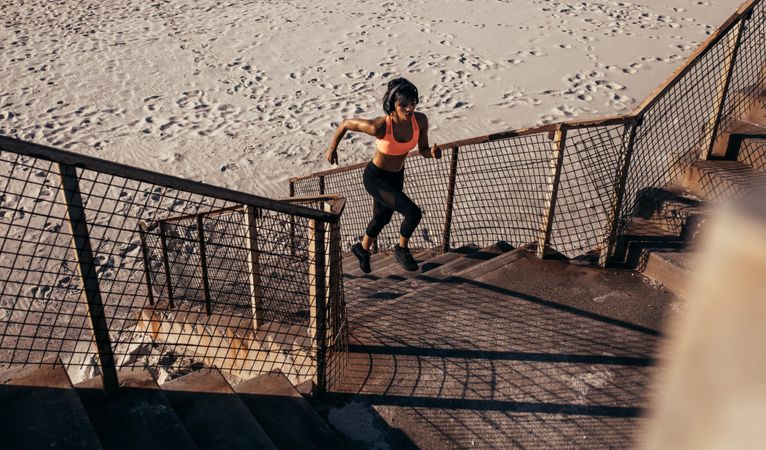 Athletic woman runs up the steps on the beach