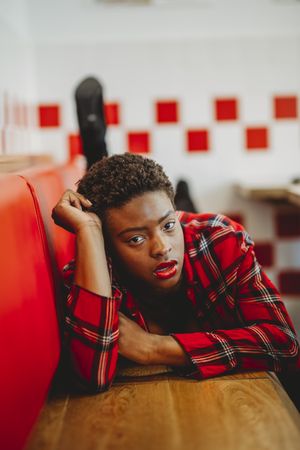 Gorgeous stylish Black woman lying on seats in cafe