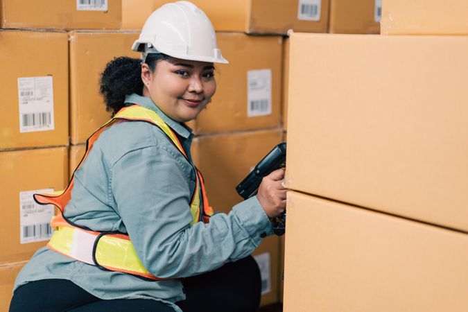 Woman in safety gear working in warehouse full of stock