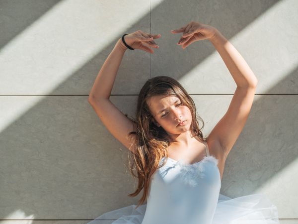 Ballerina standing in classical position near wall