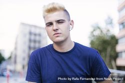 Portrait of young blond man on the street while looking at the camera 0gX9xe