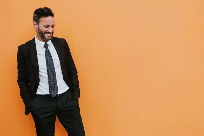 Adult stylish man in costume near orange wall