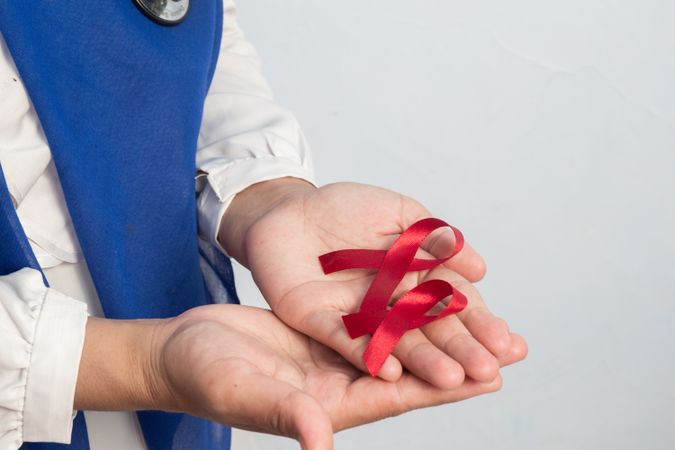 Happy Muslim Female Asian doctor or nurse holding Red ribbons, HIV awareness concept, world AIDS day, world cancer day with copy space