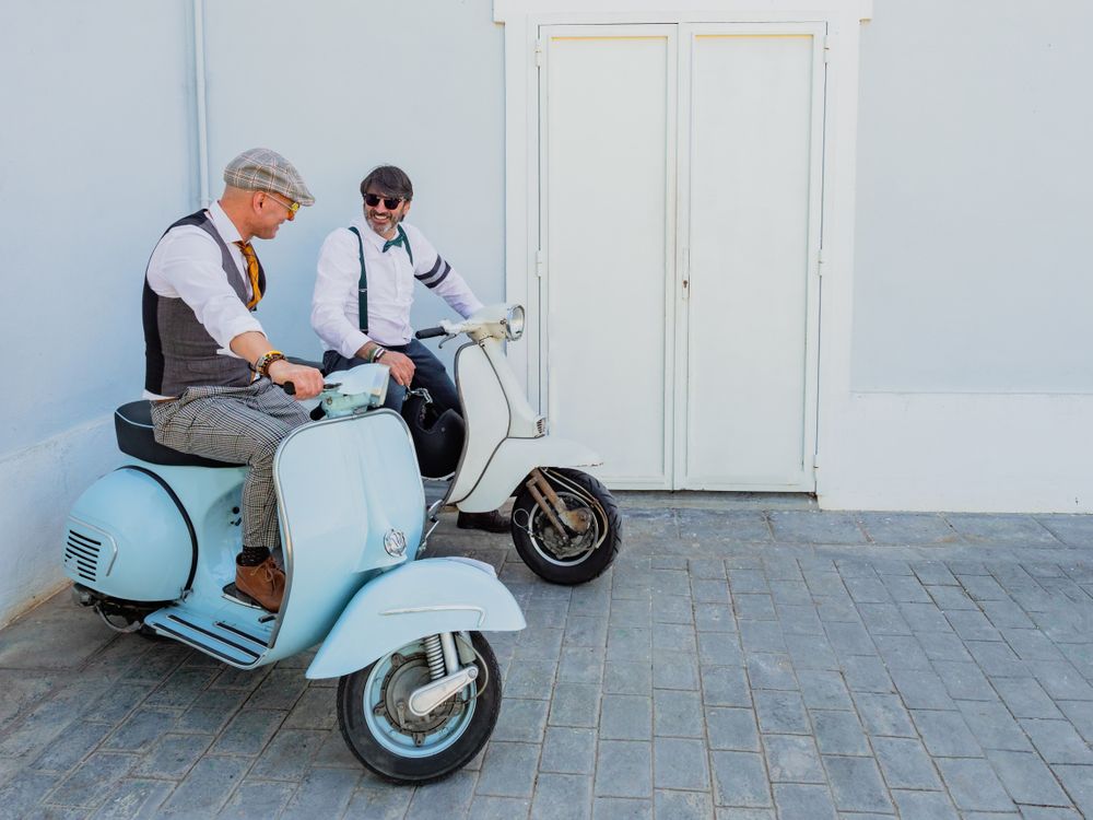 Trendy men sitting on vintage scooters