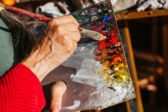 Crop artist with paint palette in workshop
