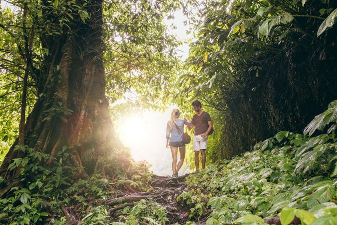Young man and woman hiking in tropical jungle