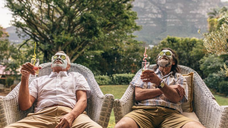 Two men with facial mask and cucumber slices on their face at spa