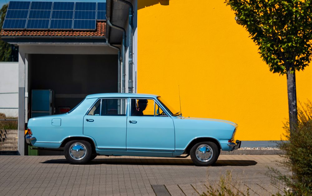 Sky blue retro car against a bright yellow wall. Color contrast.